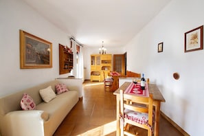Una sala de estar con un sofá, una mesa de comedor con sillas, un aparador de madera y un cuadro en la pared.
