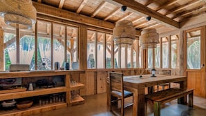 A wooden interior with a dining area, shelves, and hanging lights.