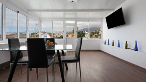 Un comedor moderno con una mesa de vidrio, sillas negras y vistas de la ciudad.
