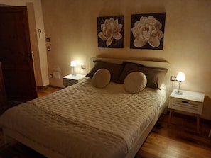 A neatly made bed with a quilted cover, two wall-mounted lamps, and two large floral paintings above the bed. - Casa Clery Tuscan Style Breakfast Included (Montelupo Fiorentino)
