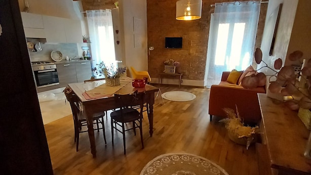 A spacious living area with a wooden floor, a dining table, and a sofa. - Casa Clery Tuscan Style Breakfast Included (Montelupo Fiorentino)