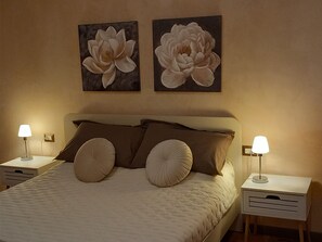 A bedroom with a bed, two nightstands, two lamps, and two wall-mounted flower paintings. - Casa Clery Tuscan Style Breakfast Included (Montelupo Fiorentino)