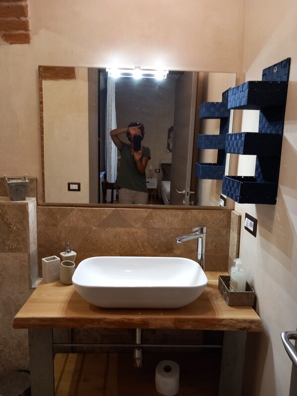 A bathroom with a large mirror, a white sink, a towel rack, and a toilet paper roll. - Casa Clery Tuscan Style Breakfast Included (Montelupo Fiorentino)