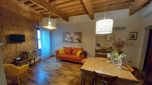Een gezellige woonkamer met een houten plafond, een bank, een eettafel en een televisie die aan de muur is bevestigd.