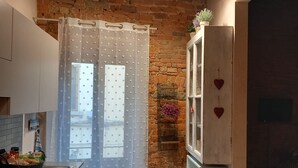 A kitchen with a stone wall, a refrigerator, a basket of bread, and a curtain. - Casa Clery Tuscan Style Breakfast Included (Montelupo Fiorentino)