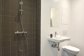 A bathroom with a shower, sink, toilet, and two mirrors.