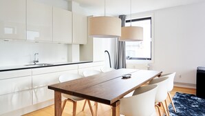 A modern kitchen with white cabinets, a wooden dining table, and two pendant lights. - Nørre Voldgade 80 (Copenhagen)