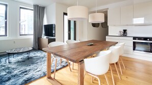 A modern kitchen with white cabinets, a wooden dining table, and a blue rug. - Nørre Voldgade 80 (Copenhagen)