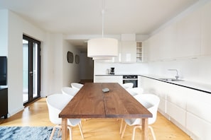 A modern kitchen with white cabinets, a wooden dining table, and white chairs.