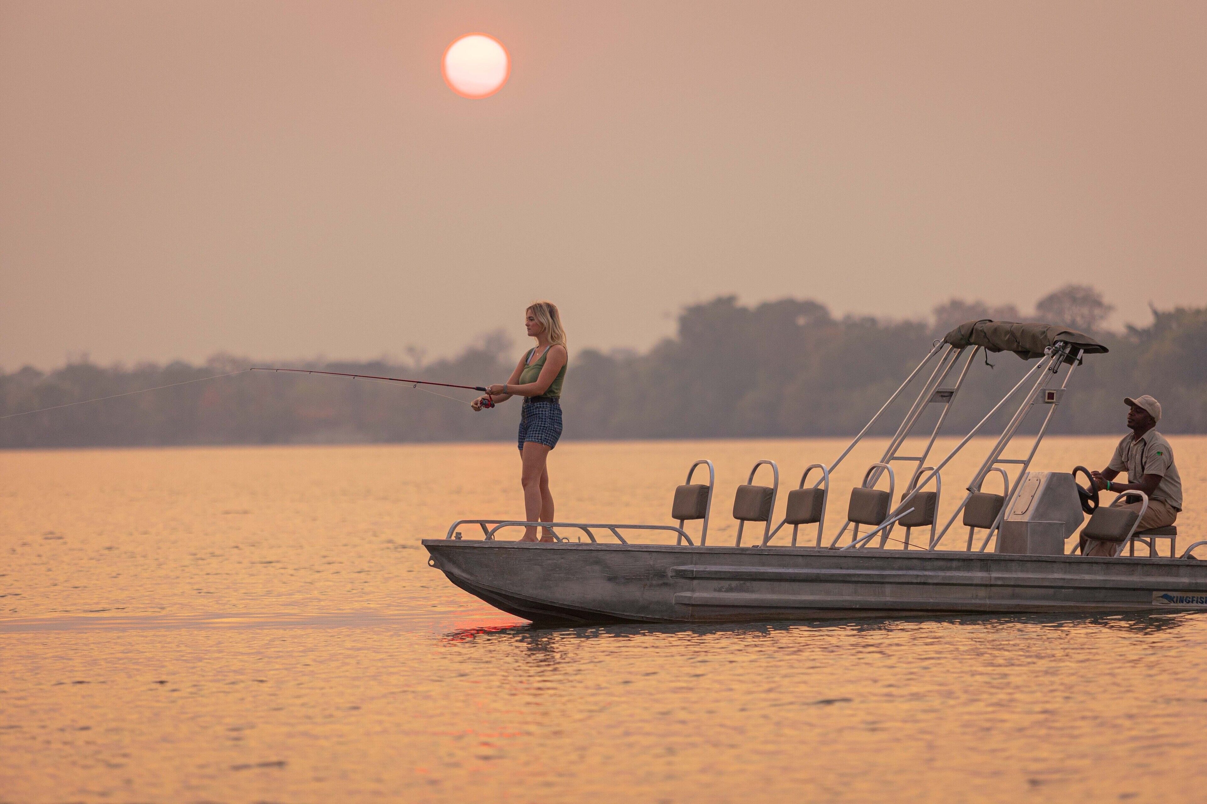 Um barco com alguém pescando e outra pessoa remando.