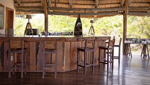 Un coin bar rustique, avec des meubles en bois et un toit de chaume.