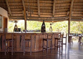 Una zona de bar rústica con muebles de madera y techo de paja.