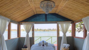 Une pièce avec un plafond en bois, un lit recouvert d’une couverture blanche, un lustre et une vue sur un lac.