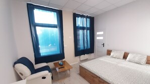 Un dormitorio moderno con una cama grande, una silla y dos ventanas con cortinas.