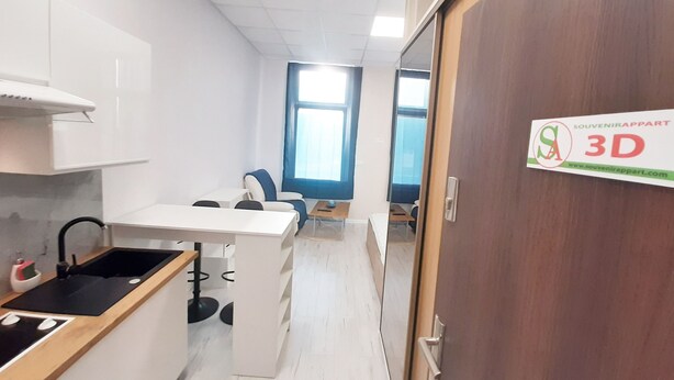 Una cocina moderna con armarios blancos, encimera negra y una puerta de madera con un cartel.