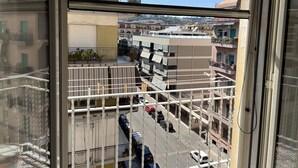 A view from a window overlooking a multi-story residential building with balconies, a street below, and a clear sky. - B&B i borboni (Naples)