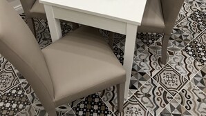 A white square table with a black candle holder and a silver tray, surrounded by beige chairs, set on a patterned floor. - B&B i borboni (Naples)