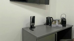 A small, modern room with a flat-screen TV mounted on the wall, a coffee maker, a kettle, and a box of tissues on a counter. - B&B i borboni (Naples)