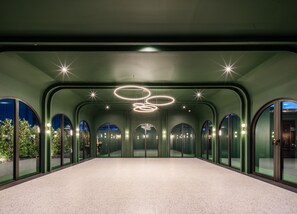 A spacious corridor with arched windows, a central light fixture, and a view of greenery outside. - Cher Hostel Bangkok (Bangkok)