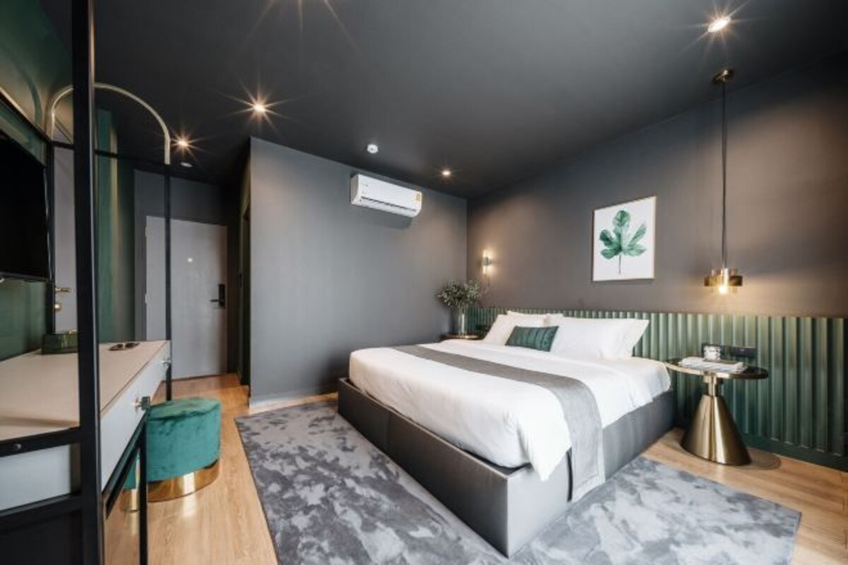 A modern bedroom with a large bed, bedside tables, a mirror, and a green accent wall.