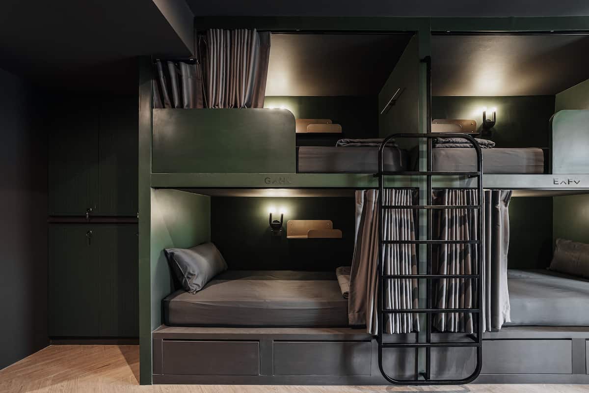A bunk bed room with a ladder, a desk, and a cabinet.