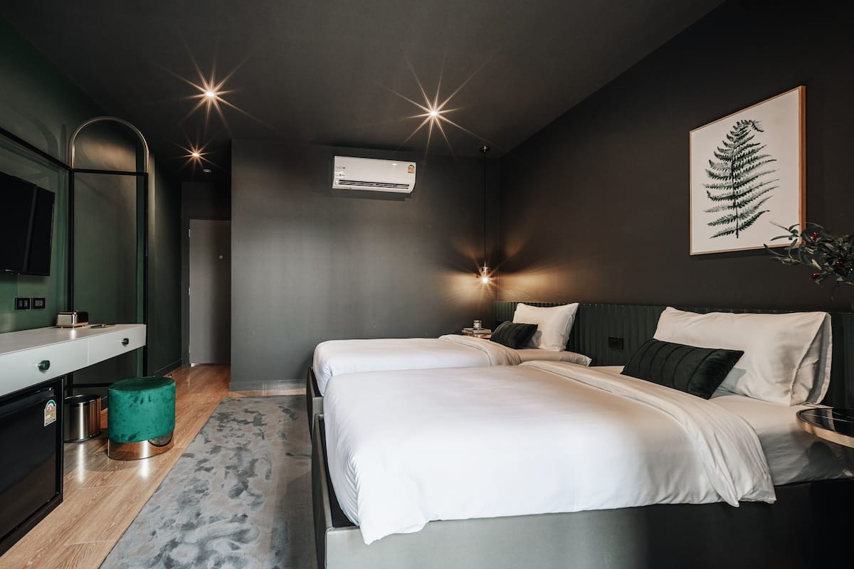 A modern bedroom with a bed, bedside tables, a mirror, and a wall-mounted air conditioner.