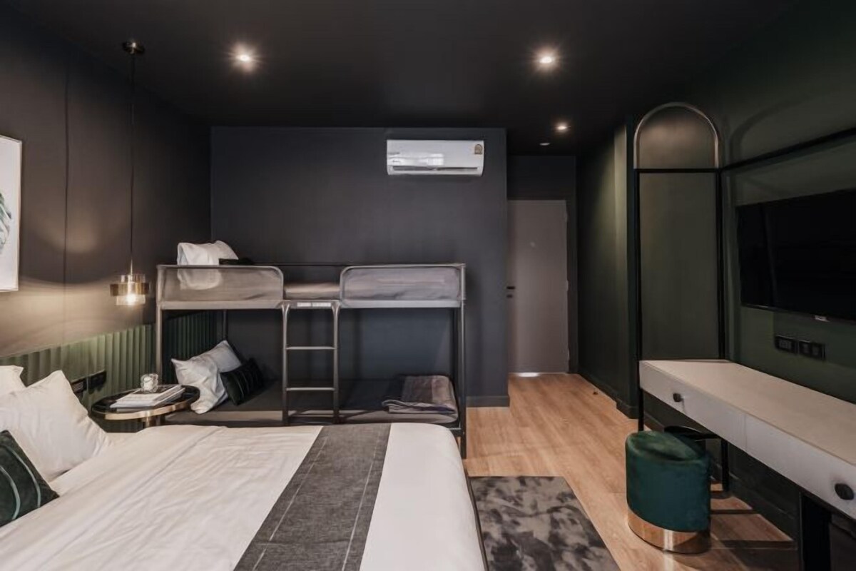 A modern hotel room with a bunk bed, a desk, a chair, and a TV.