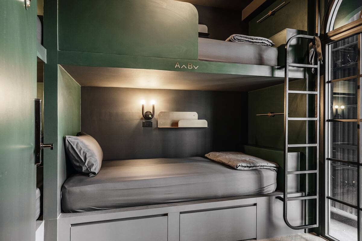 A bunk bed with a headboard, bedside tables, and a window with a view.