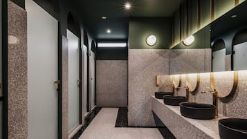 Modern restroom with sleek, contemporary design, featuring three sinks and a door with a frosted glass panel.