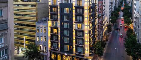 A multi-story hotel with balconies, a parking garage, and a street view.