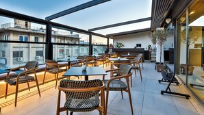 Une terrasse sur le toit avec des espaces de détente en plein air, un bar et une vue sur le paysage urbain.