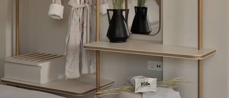 A modern bathroom with a wooden vanity, a mirror, and a robe hanging on a rack.