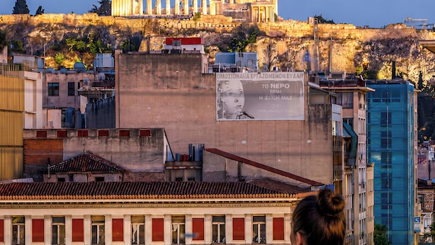 Eine Person im Schwimmbecken mit Blick auf ein historisches Gebäude und einen modernen Bau im Hintergrund.
