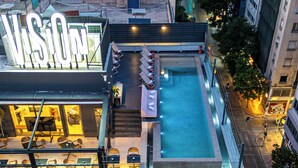Ein mehrstöckiges Gebäude mit Pool auf dem Dach und einer Sitzgelegenheit im Freien.
