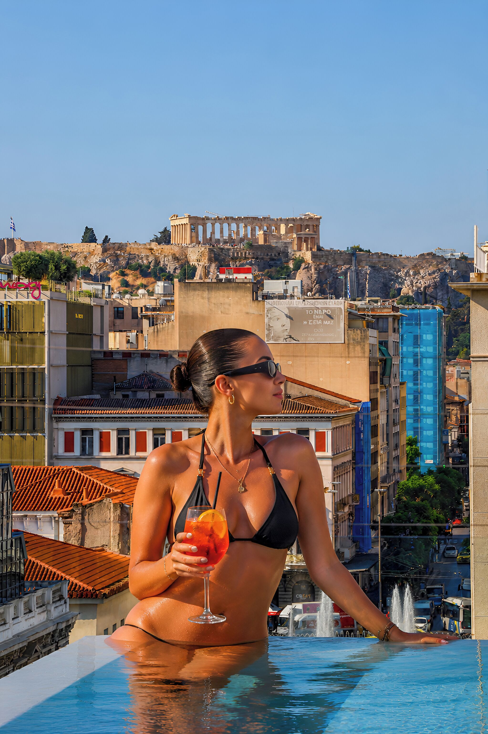 A person in a black bikini at a pool with a cityscape in the background.