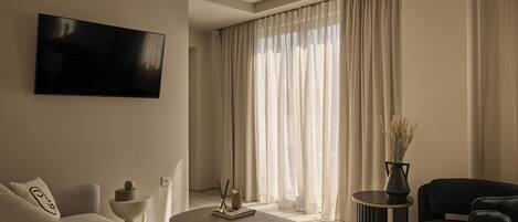 Una sala moderna con un televisor de pantalla plana, un sofá, una mesa de centro y una silla.