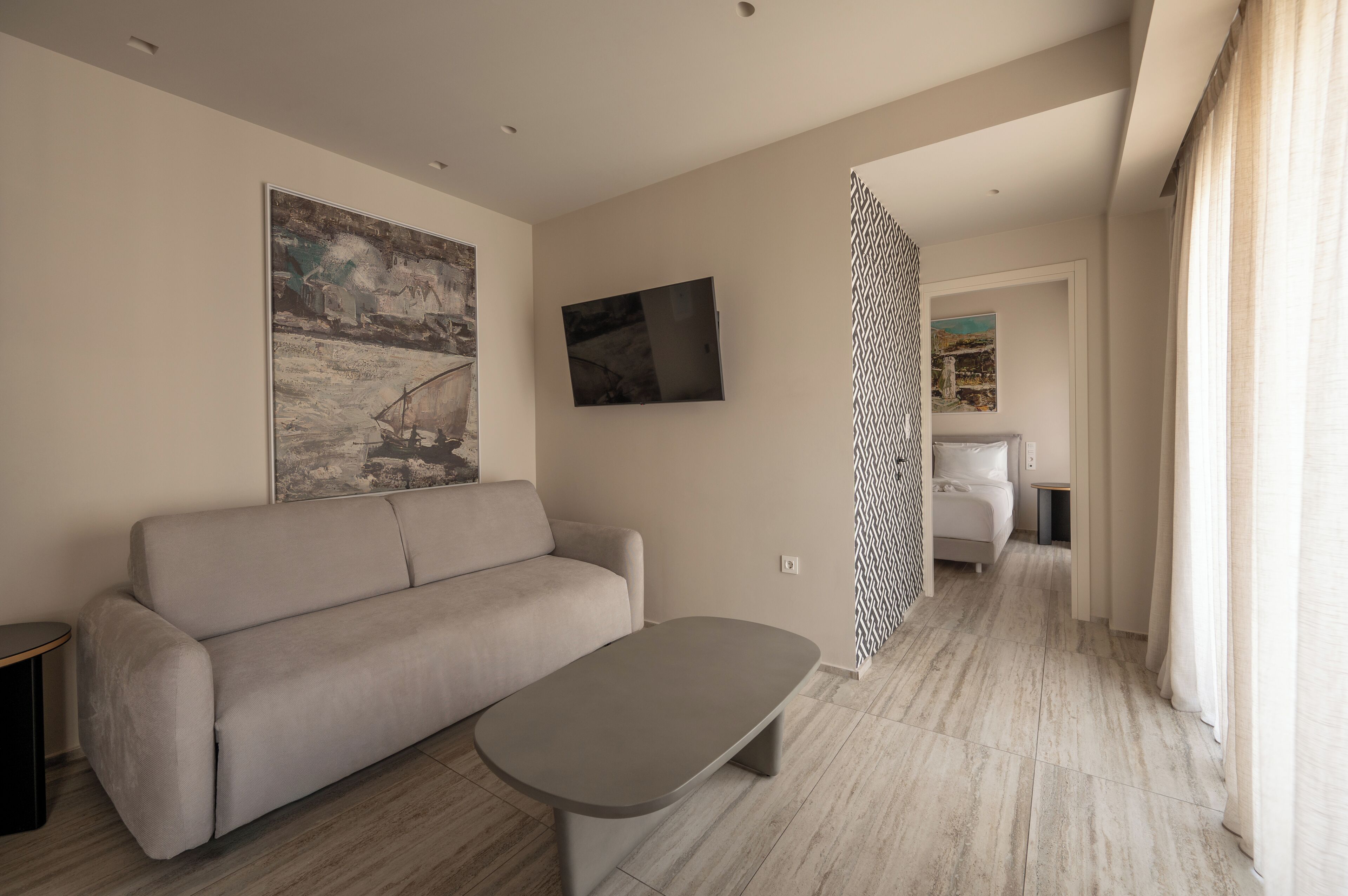 A modern living room with a sofa, a coffee table, a painting, and a TV.