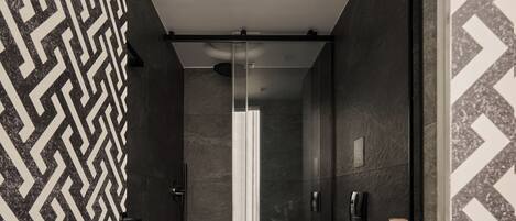 Un baño moderno con un revestimiento de pared de diseño geométrico, un inodoro blanco, un bidé y un espejo.