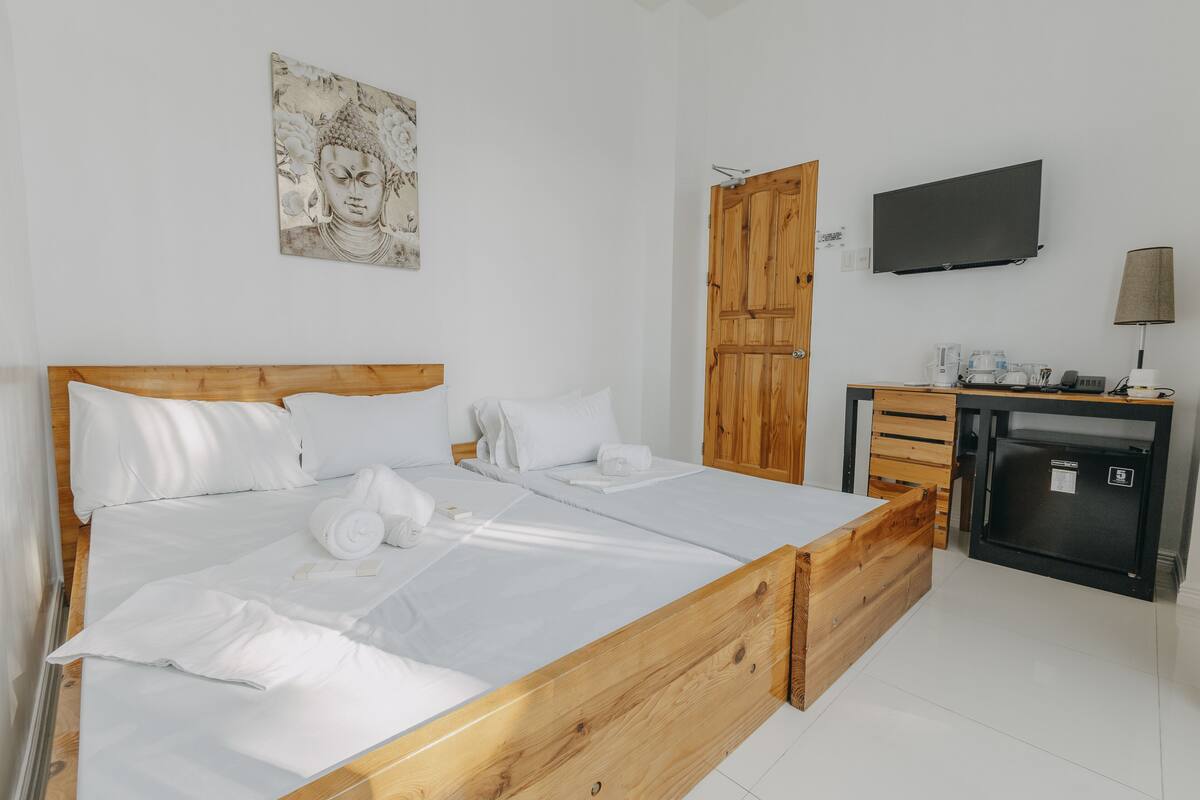 A neatly made bed with white linens, a wooden headboard, and a small bedside table with a lamp.
