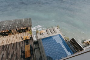 A rooftop pool with clear blue water, surrounded by wooden deck seating and lounge chairs. - The Marc Vannelli Oslob (Oslob)