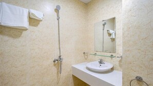 A bathroom with a white sink, a glass shelf, a handheld showerhead, a towel rack, and a mirror.