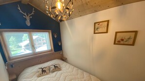 A bedroom with a bed, a window, a chandelier, and wall decorations.