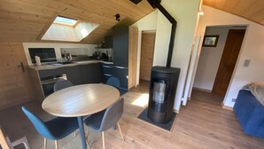 A modern kitchen with a skylight, a dining area with a round table and chairs, and a wood-burning stove.
