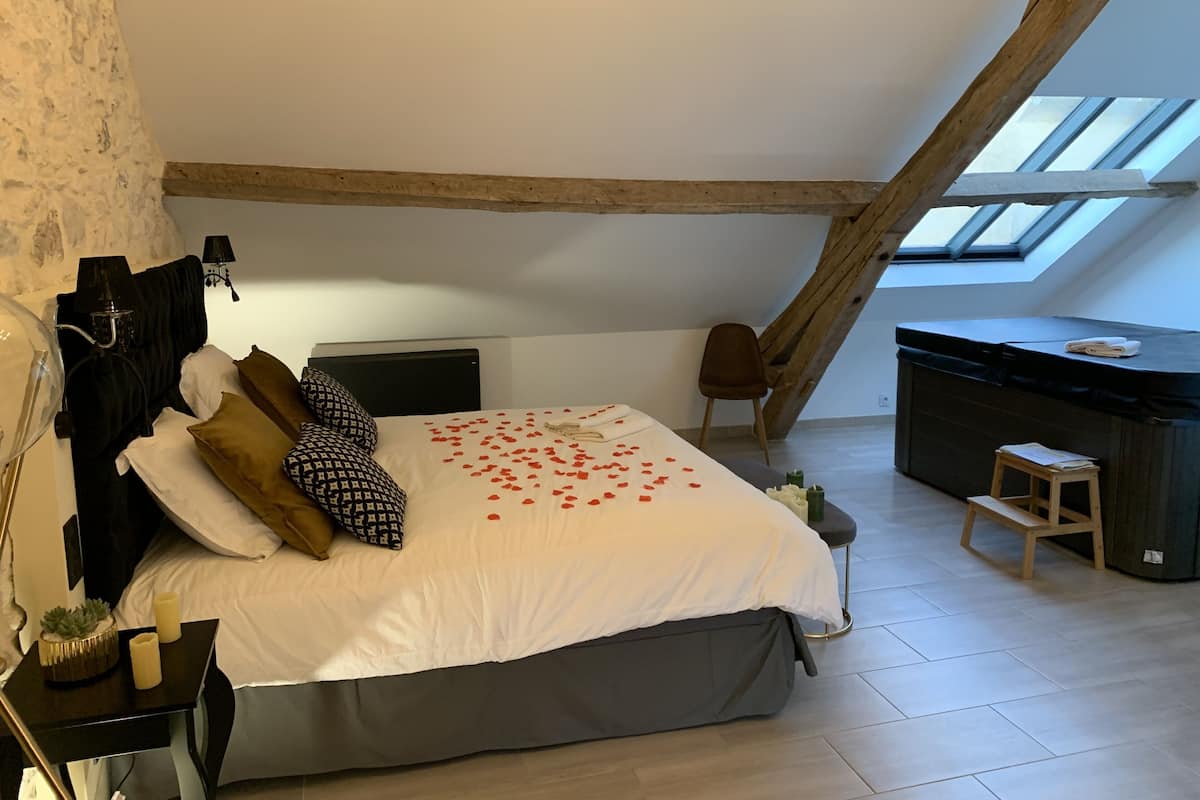 Quarto com cama, escrivaninha, cadeira e claraboia.