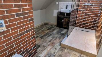 Een kleine badkamer met toilet, douchecabine met glazen deur en betegelde vloer.