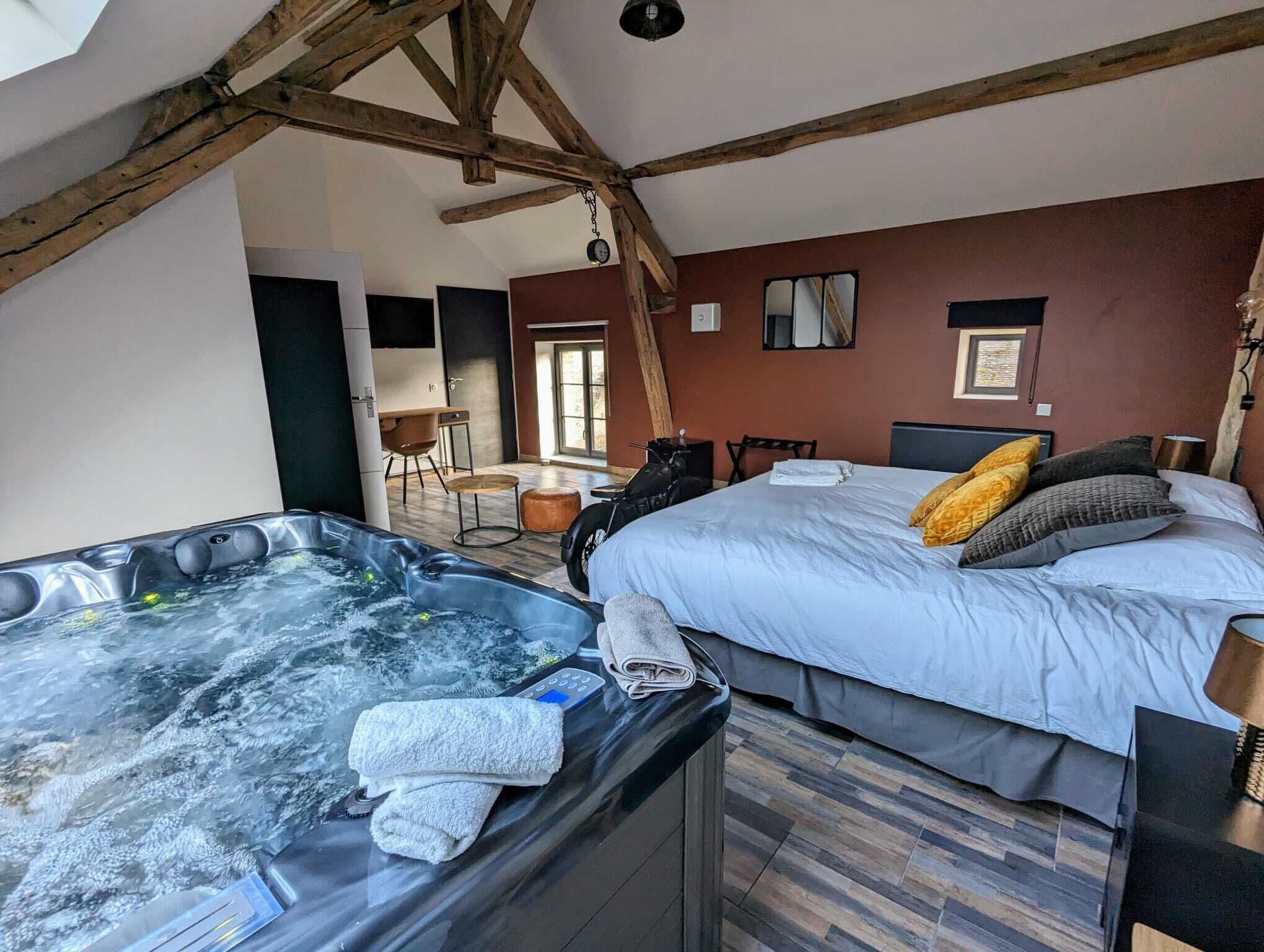 A room with a large bed, a hot tub, and a wooden ceiling.