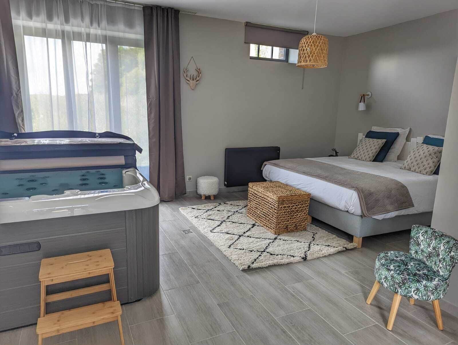A modern bedroom with a bed, a small sofa, a chair, a hot tub, and a window with curtains.