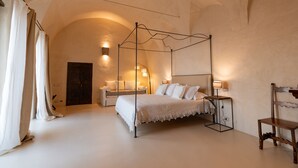 A bedroom with a four-poster bed, a bedside table with a lamp, a wooden chair, and a wardrobe. - Alma Domus ancient house recently opened in Amalfi (Amalfi)