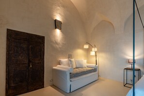 Ein gemütliches Zimmer mit einem weißen Sofa, einer Holztür und zwei Wandlampen.