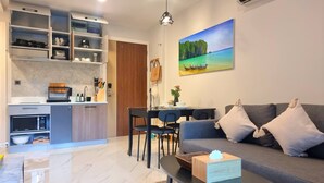 A compact living space with a kitchenette, dining area, and a sofa with cushions. - B507 - 1 Bedroom Condo Top Floor Pool View, Ao Nang (Krabi)